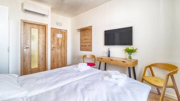 A hotel room with a bed, a desk, a chair, a TV, and a wardrobe.