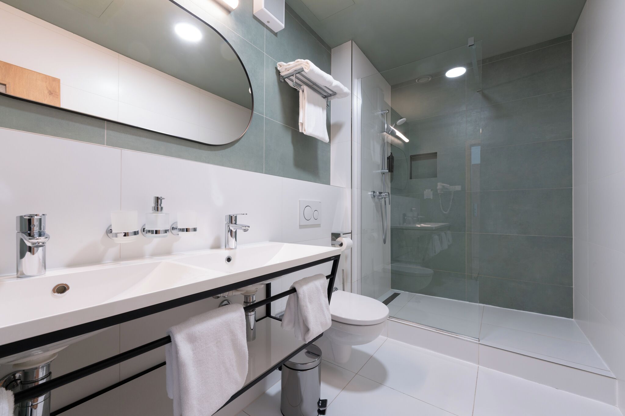A modern bathroom with a white sink, mirror, and toilet.