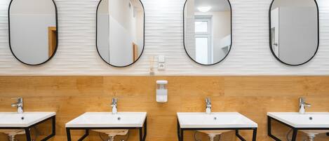 A modern bathroom with three sinks and three oval mirrors.