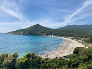 Eine Küstenlandschaft mit Strand, Berg und blauem Himmel.