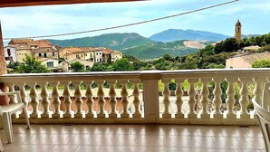 A balcony with a white balustrade overlooking a village with traditional buildings and a mountain range in the background. - Charming house near AJACCIO (Appietto)