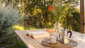 An outdoor patio with a table, chairs, a book, a cup, a vase with flowers, and a coffee maker. - Raffaello Apartment ~ LE FRAINE (New Opening 2022) (Santa Luce)