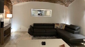 A living room with a brick ceiling, a large mirror, a dark leather sofa, and a white coffee table. - C098 Cannes - Suquet Bel appart - Grande Terrasse (Cannes)