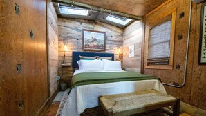 Une chambre confortable, aménagée dans une cabane en bois, avec un lit, un banc et une lucarne.