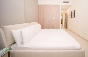 Un lit bien fait, avec du linge de lit blanc, dans une chambre d’hôtel.