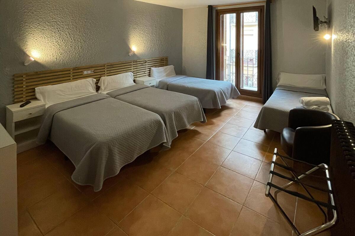 Habitación de hotel con dos camas, un escritorio, una silla y ventana con vistas.