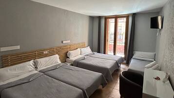 Habitación de hotel con tres camas, un escritorio y una silla.