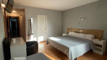 Una habitación de hotel con una cama, un escritorio, una silla y un televisor montado en la pared.