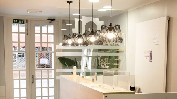 Un intérieur moderne avec un comptoir d’accueil, des luminaires suspendus et une porte en verre portant l’inscription « SORTIE ».