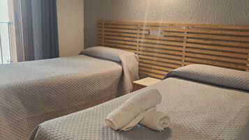 Habitació d'hotel amb dos llits, cadascun amb un llençol acolxat i un capçal de fusta.