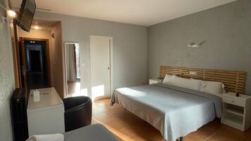 A hotel room with two beds, a desk, a chair, a mirror, and a television.