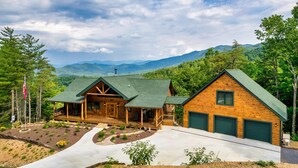 A log cabin with a green roof, a porch, and a garage.