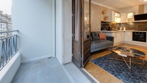 Un apartamento moderno con balcón, sofá, mesa de comedor y zona de cocina.