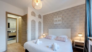 Habitación de hotel con una cama grande, mesitas de noche, un armario y un baño visible a través de una puerta abierta.