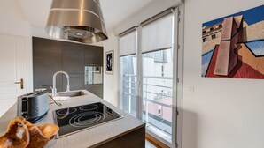 A modern kitchen with a built-in stove, a stainless steel range hood, and a window with a view of the city. - Le Kaliste*** - apartment for 4 people + garage (Annecy)