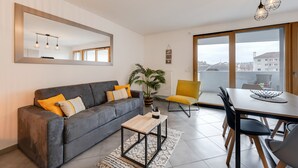 A modern living room with a grey sofa, yellow chair, and a dining table. - L'Art de Ville*** - 2  bedroom near the city center, terrace and garage (Annecy)