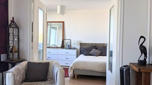 A bedroom with a bed, bedside table, dresser, and a mirror. - Charming bright T2, balcony, parking, telework (Annecy)