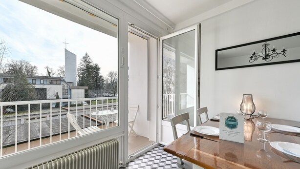 A dining area with a checkered floor, a wooden table, and a glass partition. - Le Boileau - Apartment for 4 people, parking and balcony, CLOSE to the Lake (Annecy)