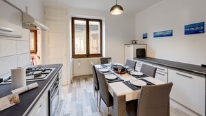 A modern kitchen with a dining area, featuring a gas stove, a built-in oven, a refrigerator, and a large window.