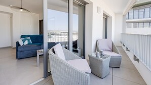 A balcony with wicker furniture, a sofa, and a glass door leading to an outdoor area. - La Cantonade - Nice T2 with garage for 4 people near Beach (Annecy)