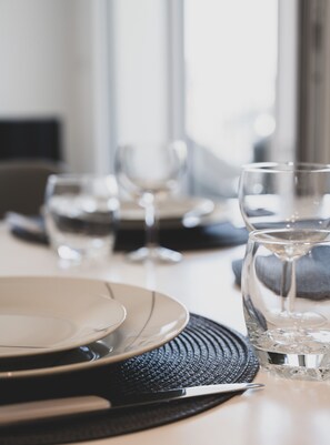 A dining table set with plates, glasses, and a water glass.