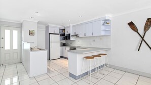 Een moderne keuken met witte kasten, een centraal eiland met krukken en een eethoek.