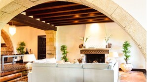 Un salon chaleureux avec une cheminée en pierre, un canapé et une table avec une lampe.