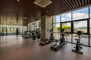 Ein Fitnessstudio mit unterschiedlichen Trainingsgeräten, großen Fenstern und Blick ins Freie.