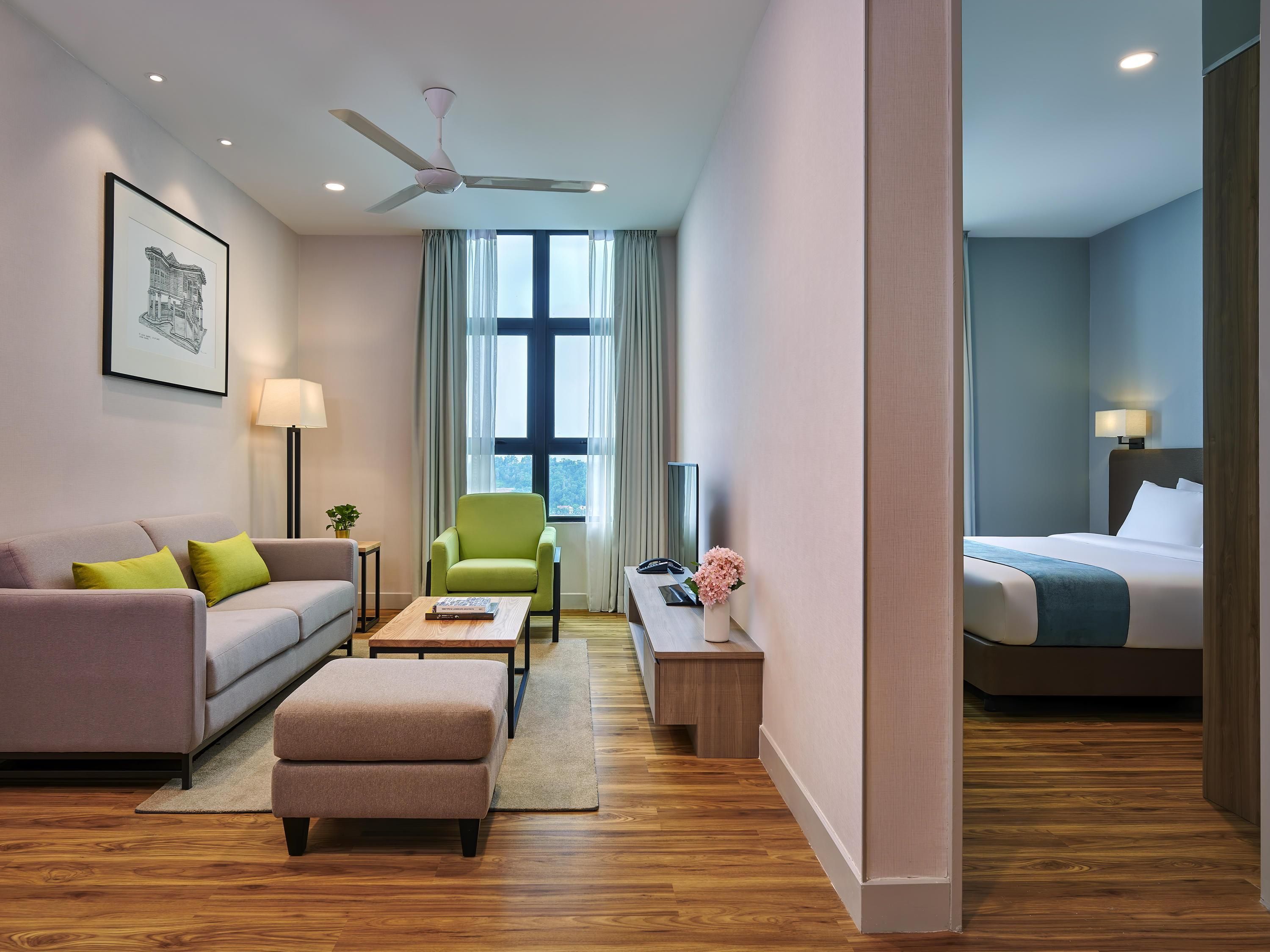Une chambre d’hôtel comprenant un canapé, un fauteuil, un pouf, une table de chevet, une lampe et un lit.