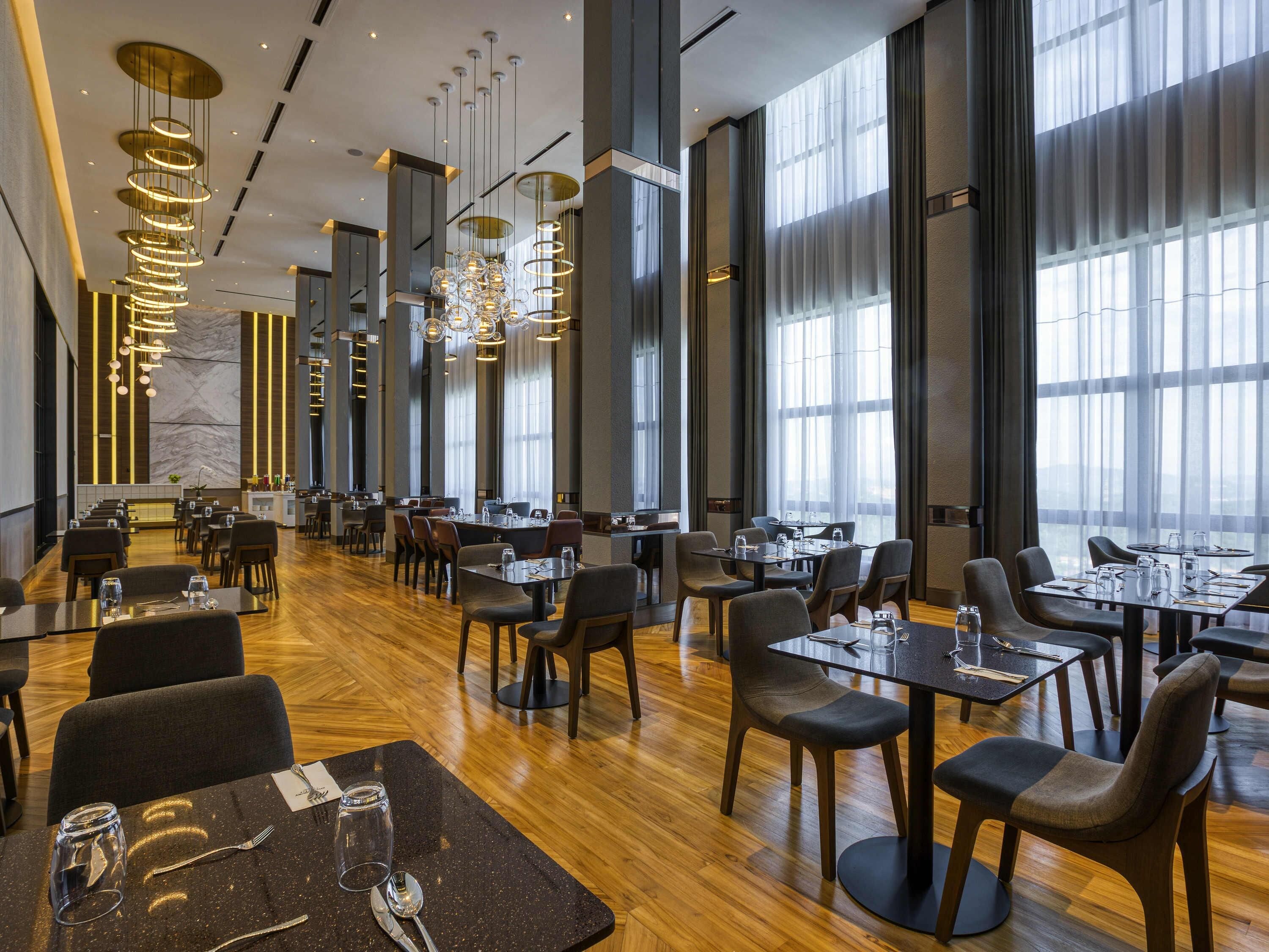 Un restaurante moderno con techos altos, amplias ventanas y luminarias contemporáneas.