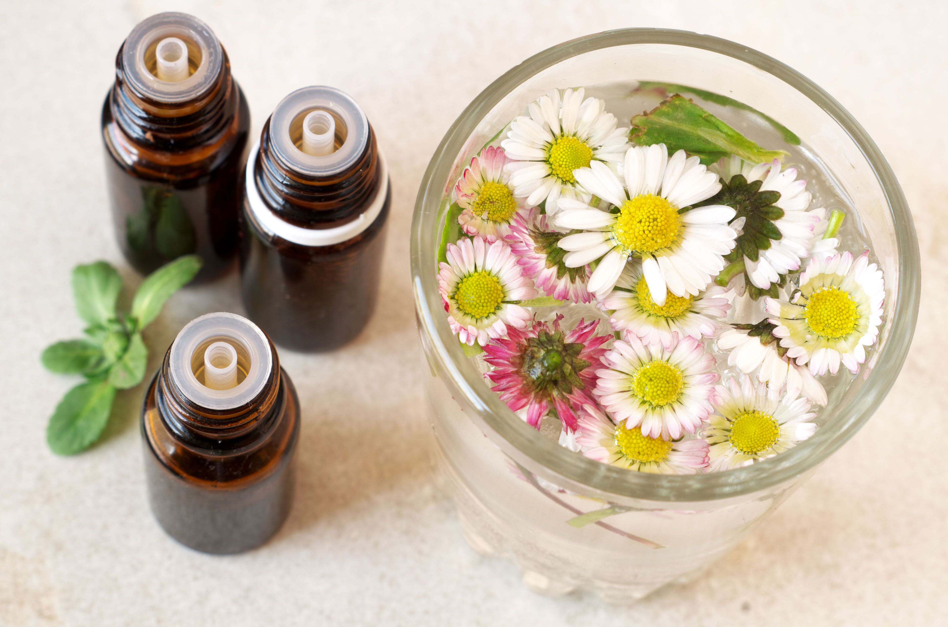 A glass container with flowers and four small bottles.