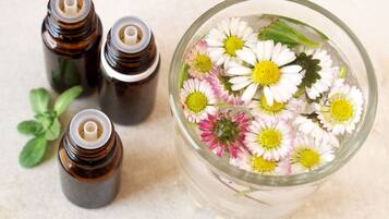 A glass container with flowers and four small bottles.