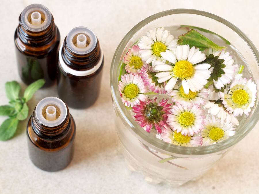 A glass container with flowers and four small bottles.