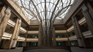 Un vaste atrium doté d’une colonne centrale et d’un plafond en verre, de nombreux balcons et d’une rambarde circulaire.