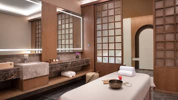 Enjoy a spa experience in this serene bathroom with a massage table, large mirror, and marble sink.