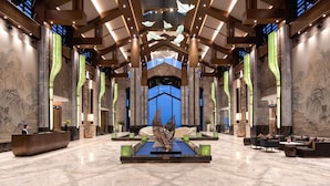 A spacious lobby with a reception desk, seating areas, and a central water feature.