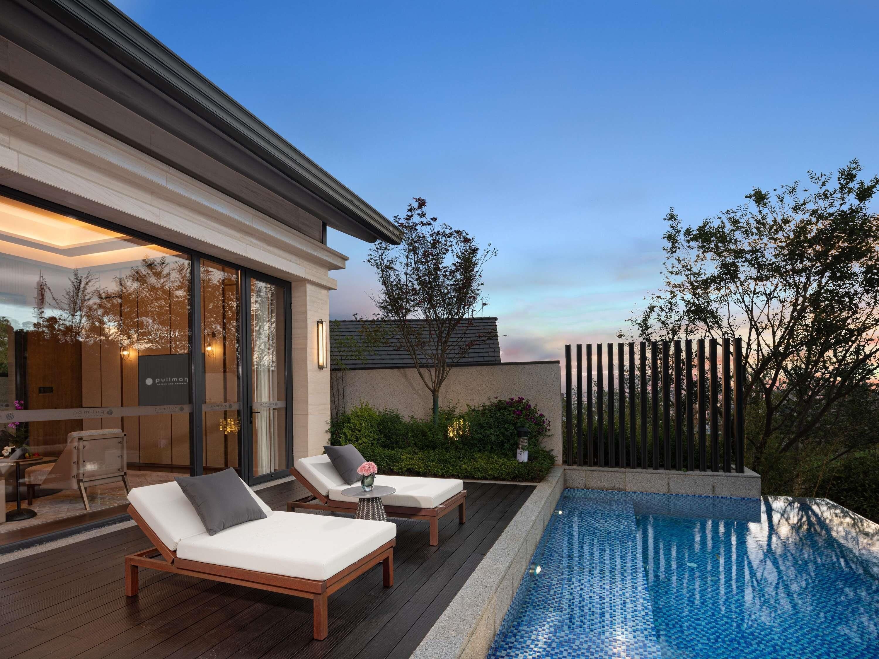 A modern outdoor pool area with lounge chairs and a wooden deck.
