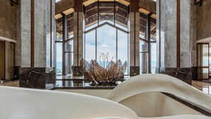 A spacious lobby with high ceilings, large windows, and a central decorative piece.