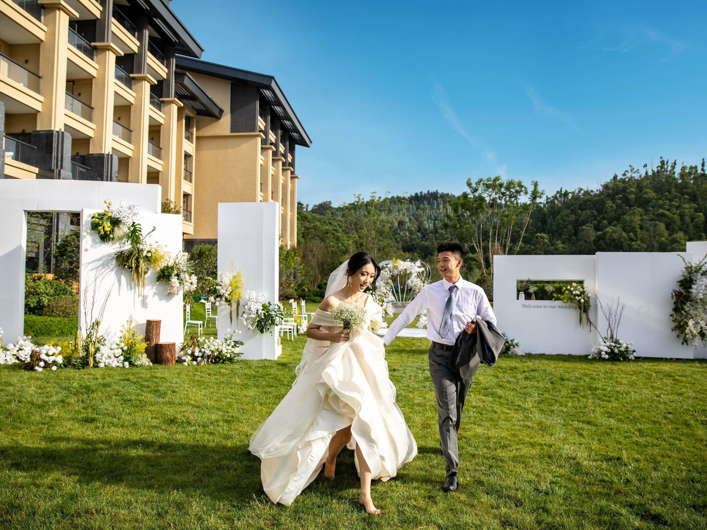 A wedding ceremony outdoors with a building in the background.