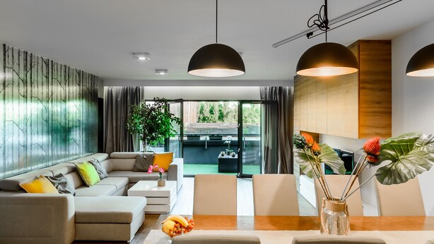 A modern living room with a sectional sofa, a dining table, and pendant lighting. - Lumina luxury apartment with 3 terraces (Lodz)