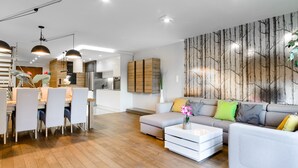 A modern living room with a dining area, a sofa, and a coffee table. - Lumina luxury apartment with 3 terraces (Lodz)
