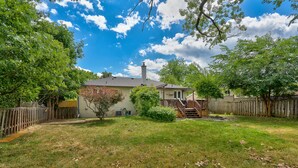 A residential backyard with a house, wooden fence, and a tree.