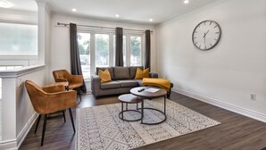 A modern living room with a sofa, two armchairs, a coffee table, and a rug.