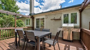 An outdoor deck with a table and chairs, a grill, and a chimney.