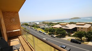 Ein Balkon mit Blick auf eine Küstenstraße, Häuser und einen Strand.