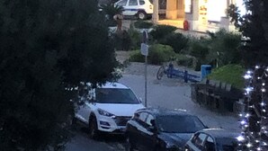 Une zone côtière où sont garées des voitures, un bâtiment dont l’entrée est illuminée, et une vue sur la mer.
