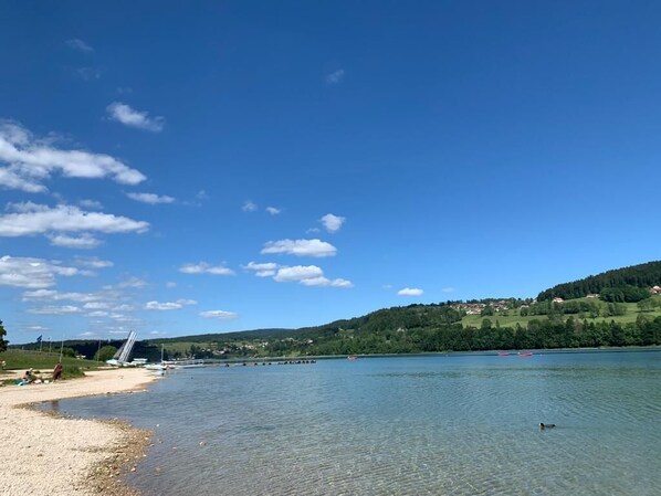 Ein klarer See mit einer Brücke und Hügeln im Hintergrund.