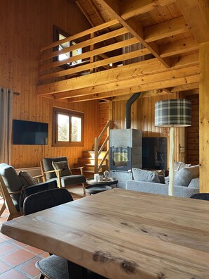 Ein Holzblockhaus-Innenraum mit Kamin, Sitzecke und einem an der Wand montierten Fernseher.