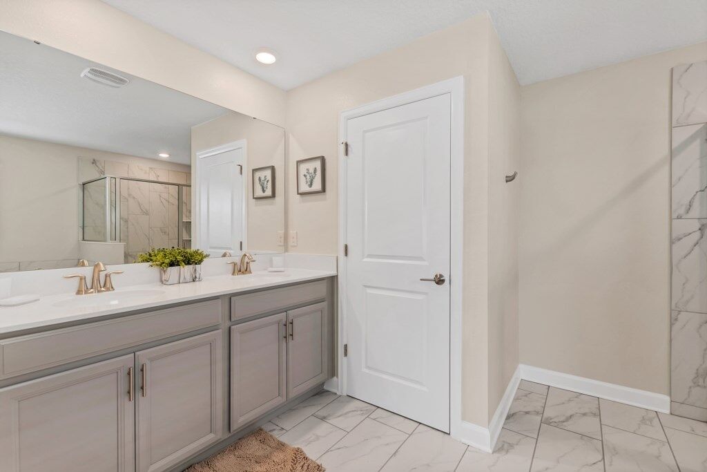 A modern bathroom with two sinks, a large mirror, and marble flooring.