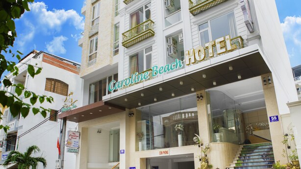 Een hotel met een opvallend bord, meerdere balkons en een trap die naar de ingang leidt.